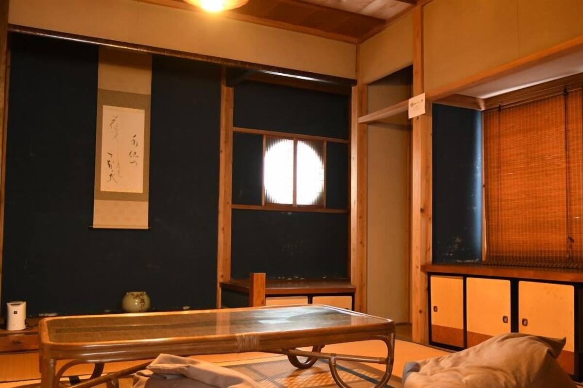 A traditional Japanese room with tatami flooring, a low table, a shoji screen, and a sliding door.
