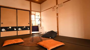 A tatami mat room with a low table, two cushions, and a hanging coat rack.