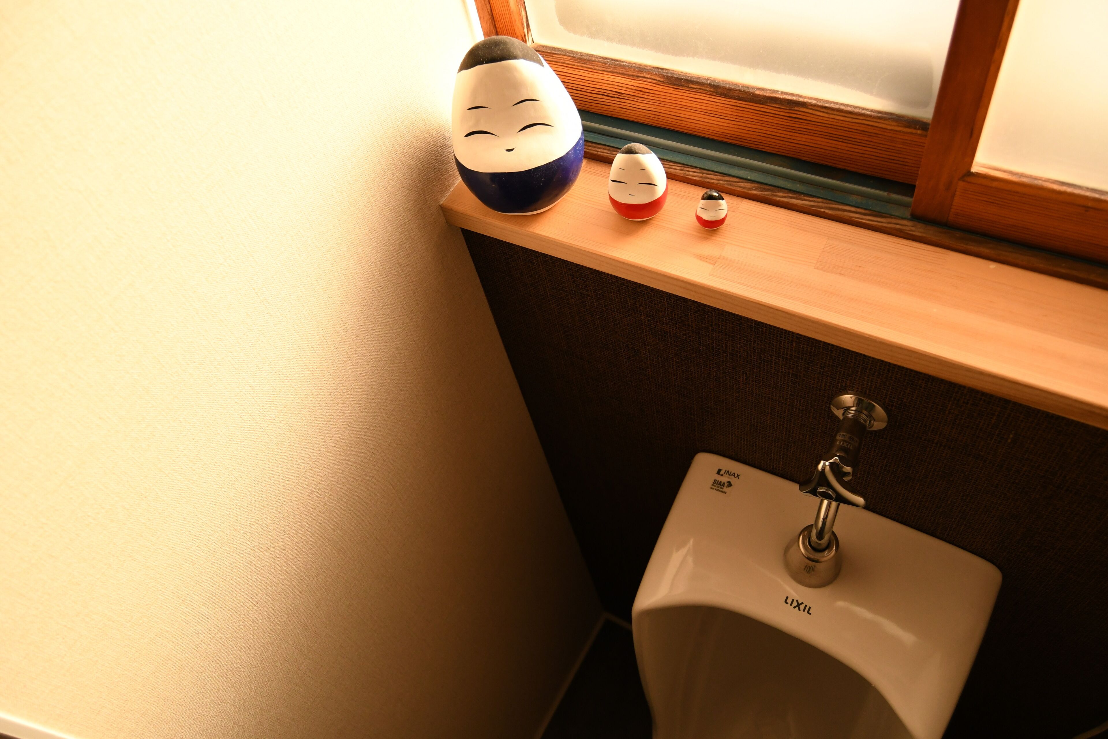 A bathroom with a sink, a window, and a shelf with decorative items.