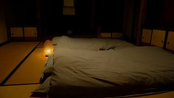 Una habitación japonesa tradicional con suelo de tatami, una cama de madera baja y una pequeña mesa con una vela.