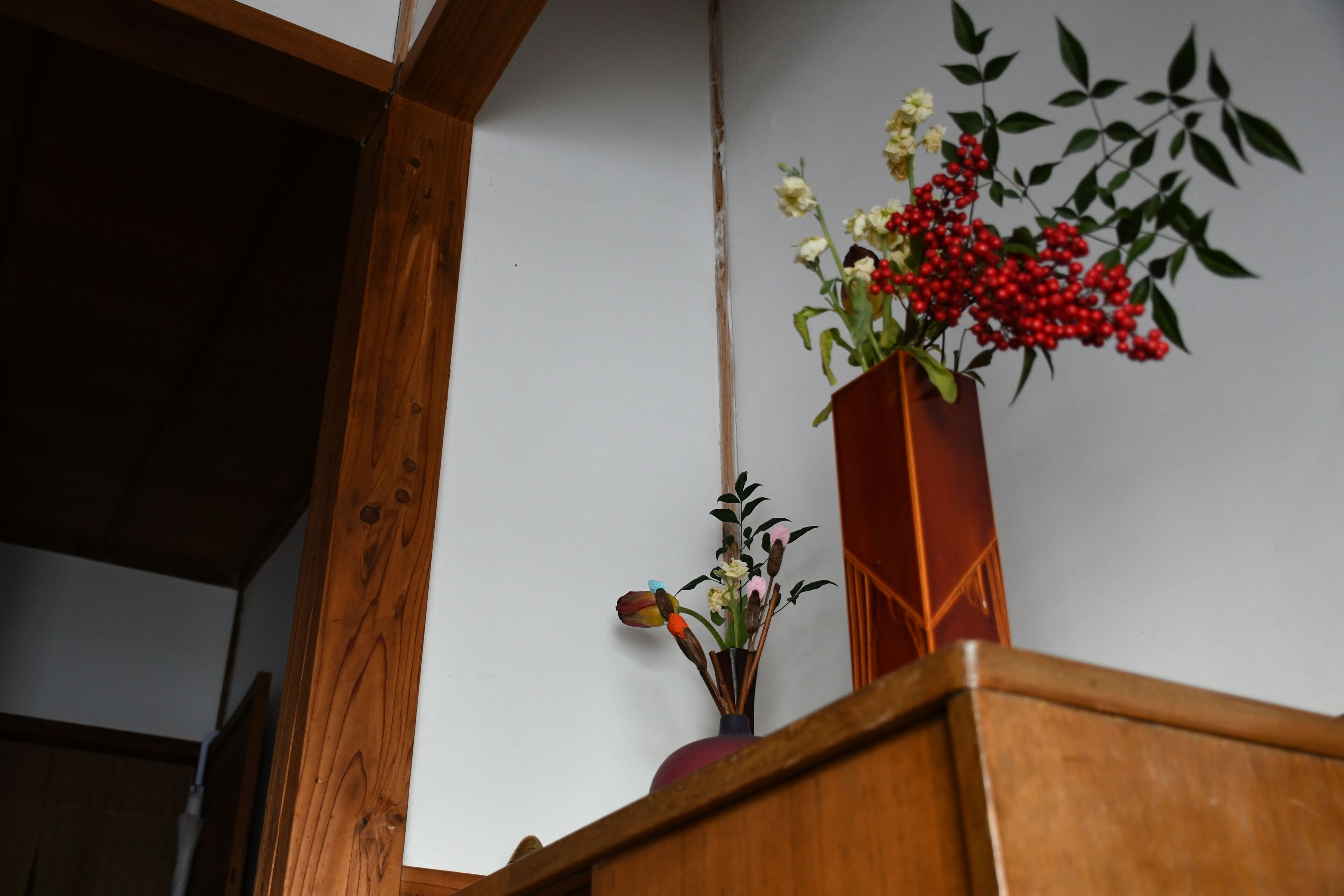 A wooden bench with a vase of flowers on it.