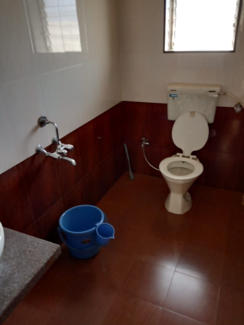 Un baño con un inodoro, un cubo azul y un grifo.