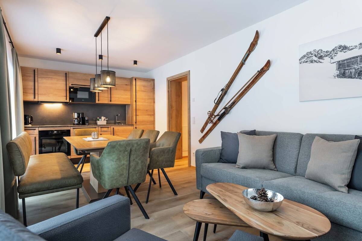 A modern living room with a grey sofa, a wooden coffee table, and a dining area with a table and chairs.