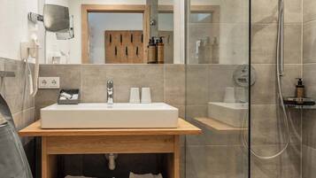 A modern bathroom with a large mirror, a wooden vanity, a glass shower enclosure, and a toilet.