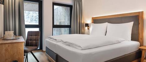 Una habitación de hotel moderna con una cama grande, un escritorio y una silla.
