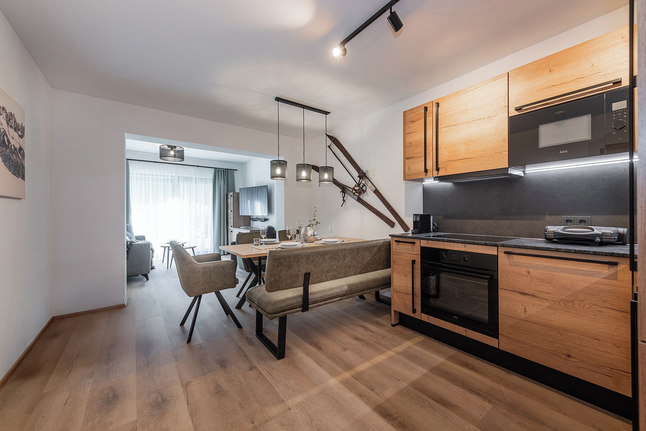 Una cocina moderna con armarios de madera, horno empotrado y comedor con banco y sillas.