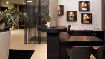 A modern interior with a round dining table, two chairs, a potted plant, and wall-mounted shelves with items.