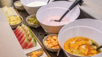 A buffet with various fruits and a bowl of soup.