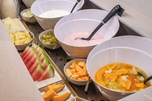 Un bufé con diversas frutas y un tazón de sopa.
