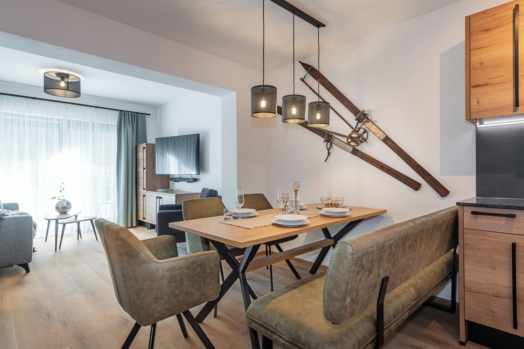 Ein moderner Essbereich mit Holztisch, gepolsterten Stühlen und Pendelleuchten.