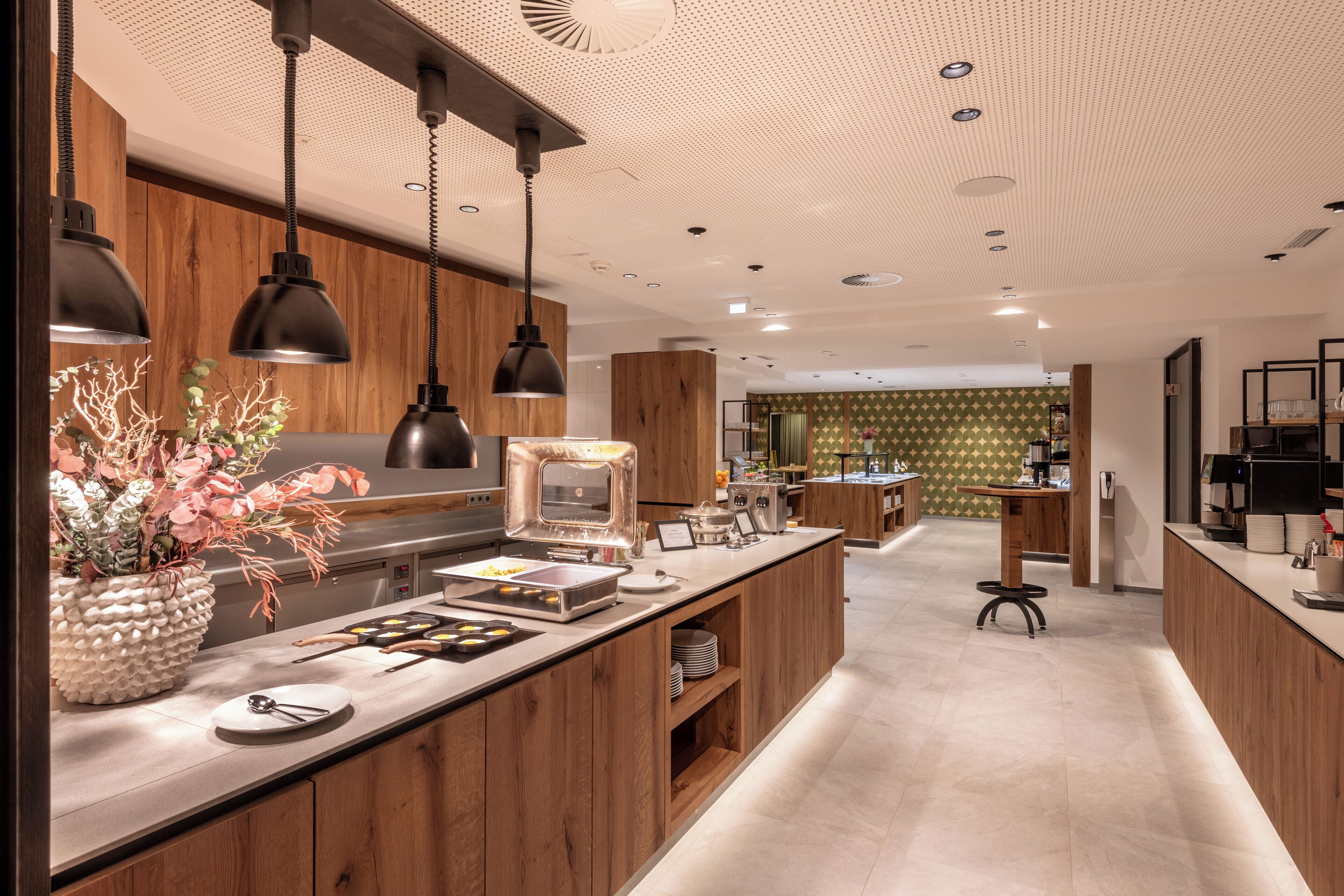 Une cuisine moderne avec des meubles en bois, des luminaires suspendus et un îlot central aménagé en buffet.