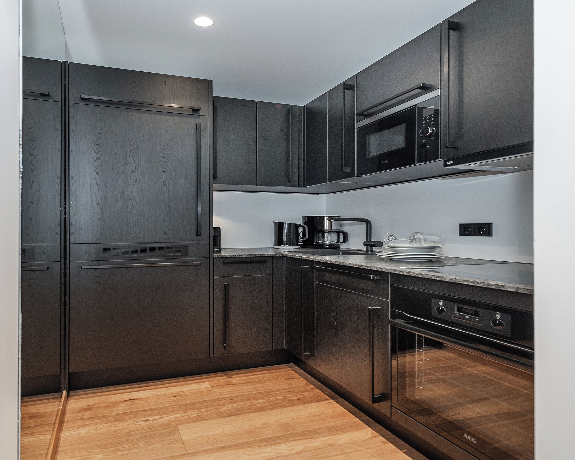A modern kitchen with dark wood cabinets, a stainless steel refrigerator, a microwave, and a coffee maker on the countertop.