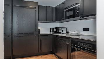 A modern kitchen with dark wood cabinets, a stainless steel refrigerator, a microwave, and a coffee maker on the countertop.