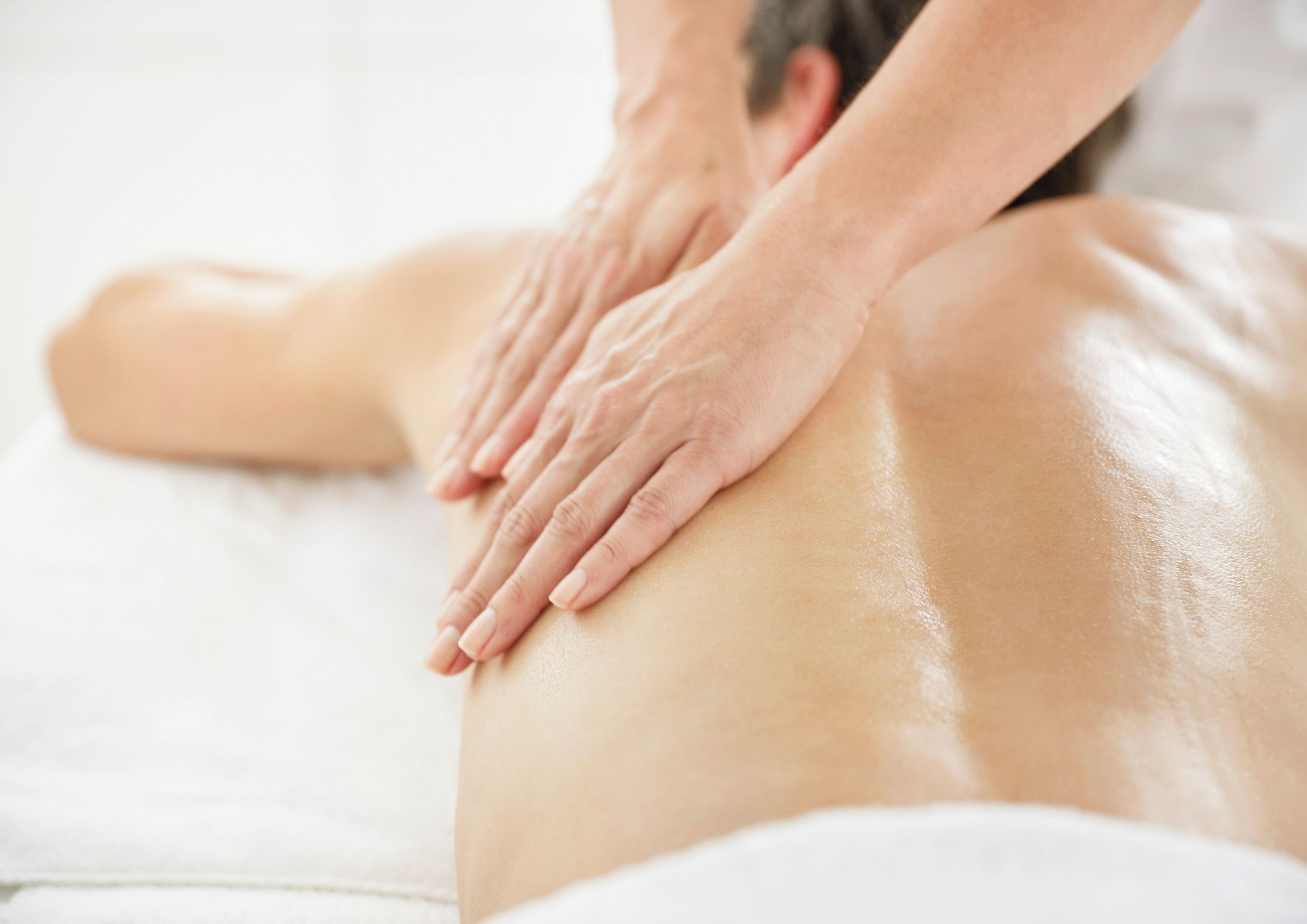 A person receiving a back massage on a white massage table.