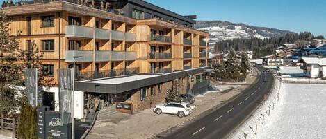 Un hotel de varios pisos con fachada de madera, balcones y un paisaje de estación de esquí.