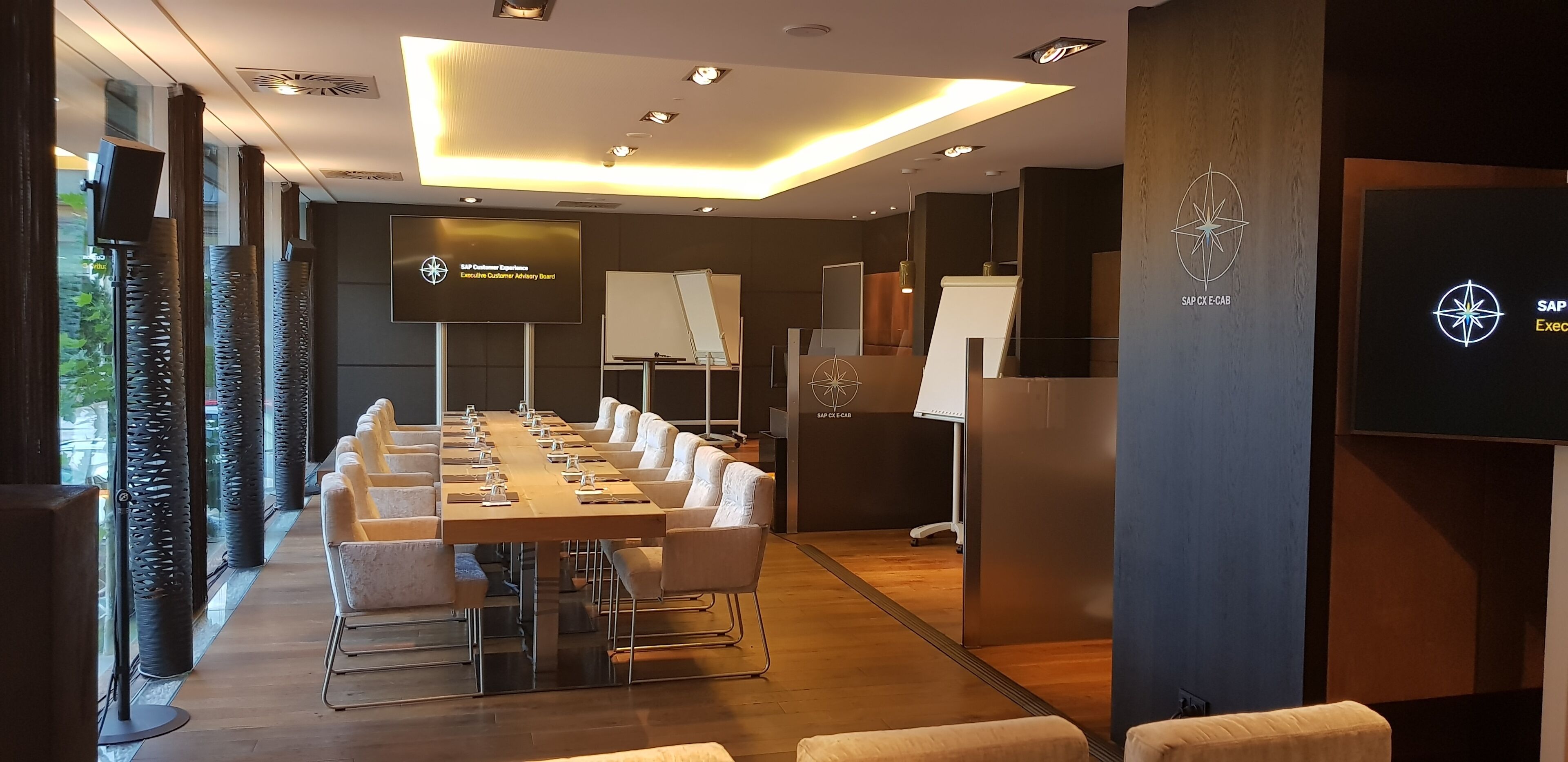 Une salle de conférence équipée d’une longue table, de chaises, d’un tableau blanc et d’un écran affichant le message « SAP Conference Experience Executive Customer Advisory Board ».