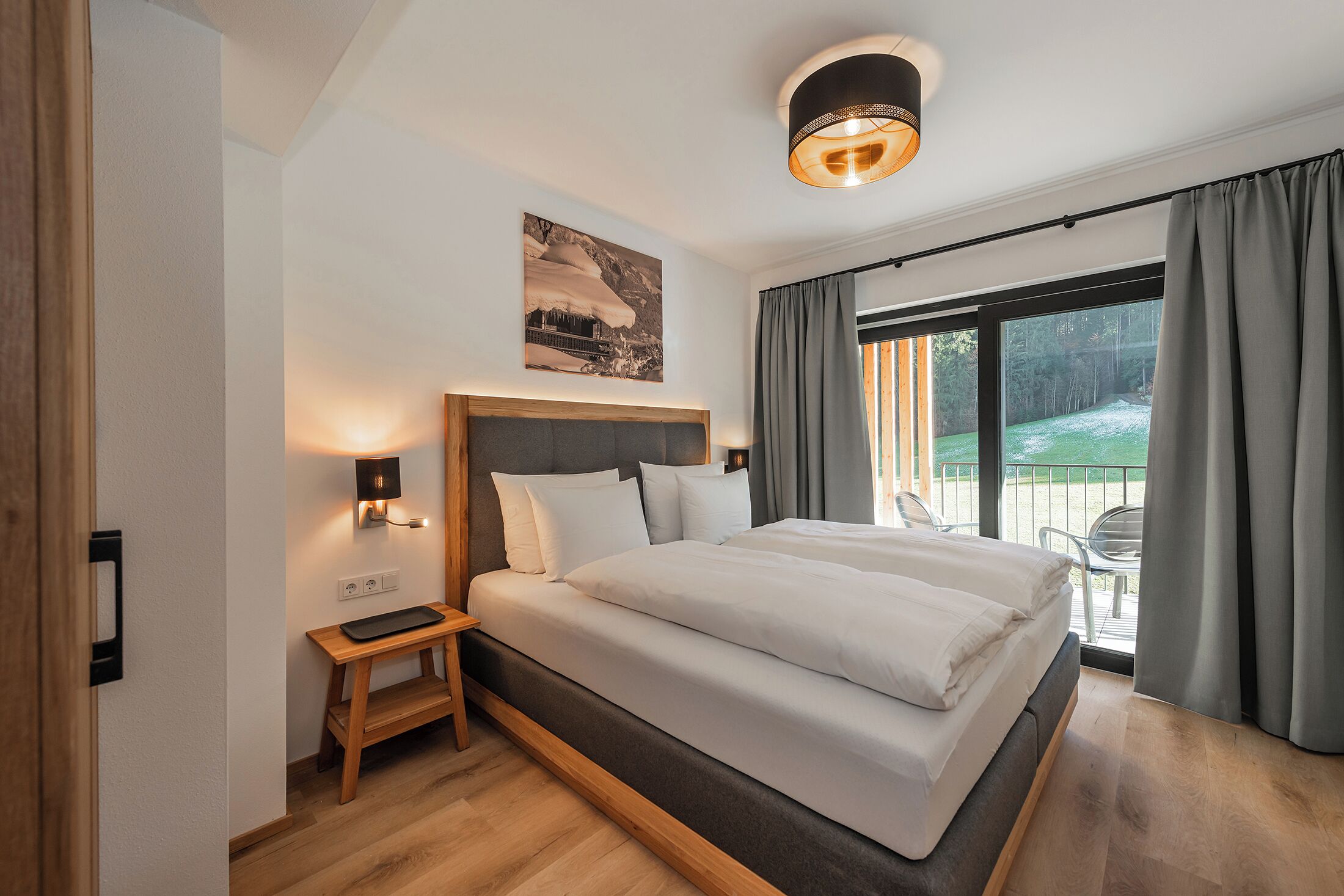 Un dormitorio moderno con una cama grande, una mesita de noche y vistas a un balcón.