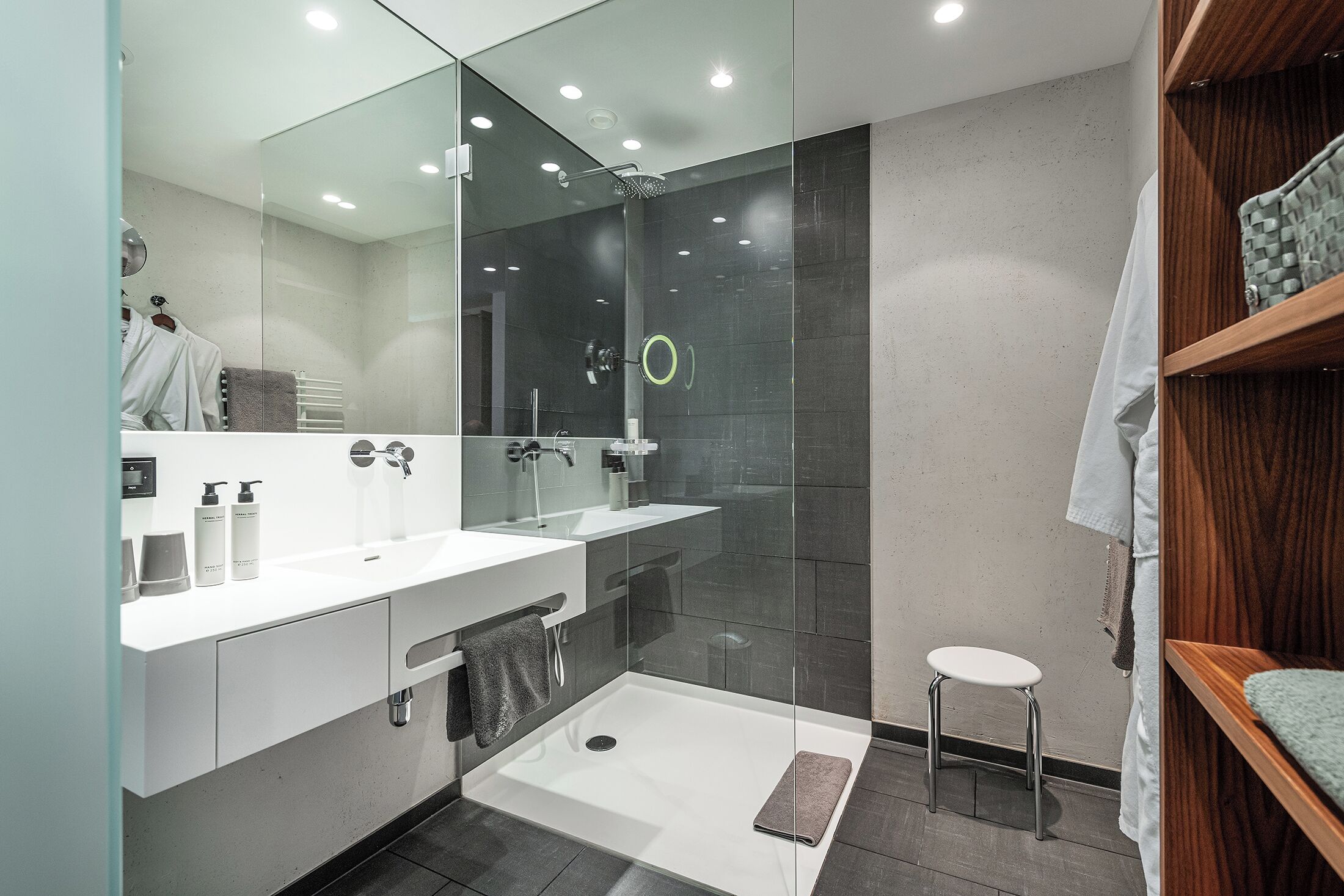 A modern bathroom with a glass-enclosed shower, a white sink, and a wooden vanity.