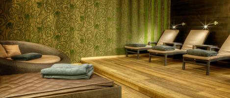 Ein Spa-Raum mit Holzboden, einer Massageliege und zwei Massage-Stühlen.