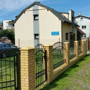 Ein Wohngebäude mit einer beigen Fassade, einem blauen Schild und einem schwarzen schmiedeeisernen Zaun.