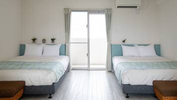 Een hotelkamer met twee bedden, een schuifdeur en een kleine potplant op elk bed.