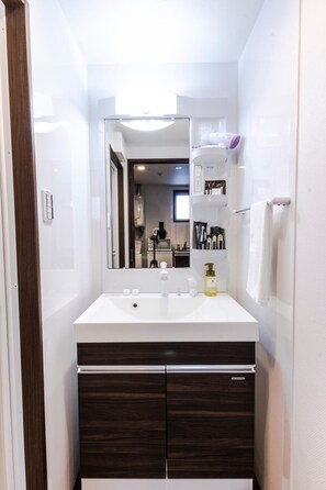 Une salle de bain moderne avec un lavabo blanc, un meuble-lavabo en bois foncé et un miroir.
