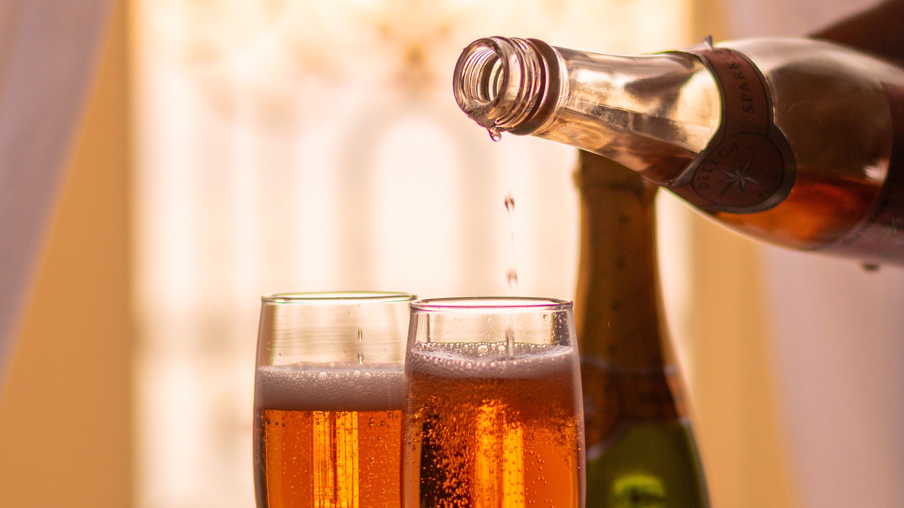 Eine Flasche gießt Flüssigkeit in zwei Gläser.
