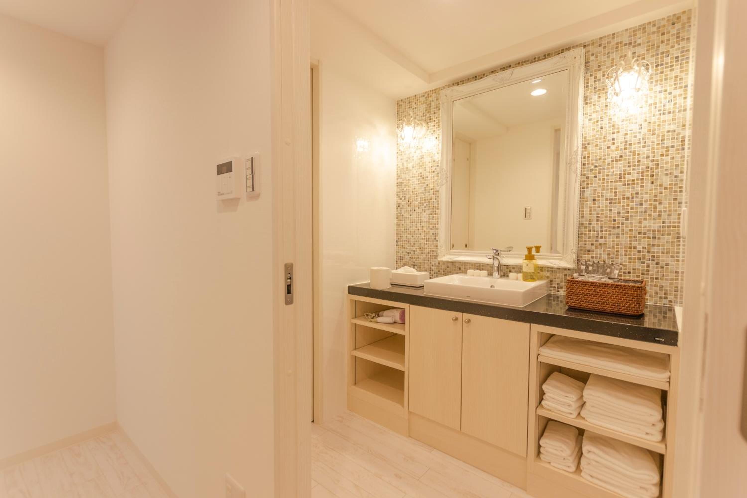 A bathroom with a large mirror, a sink, and shelves for towels.