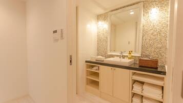 A bathroom with a large mirror, a sink, and shelves for towels.