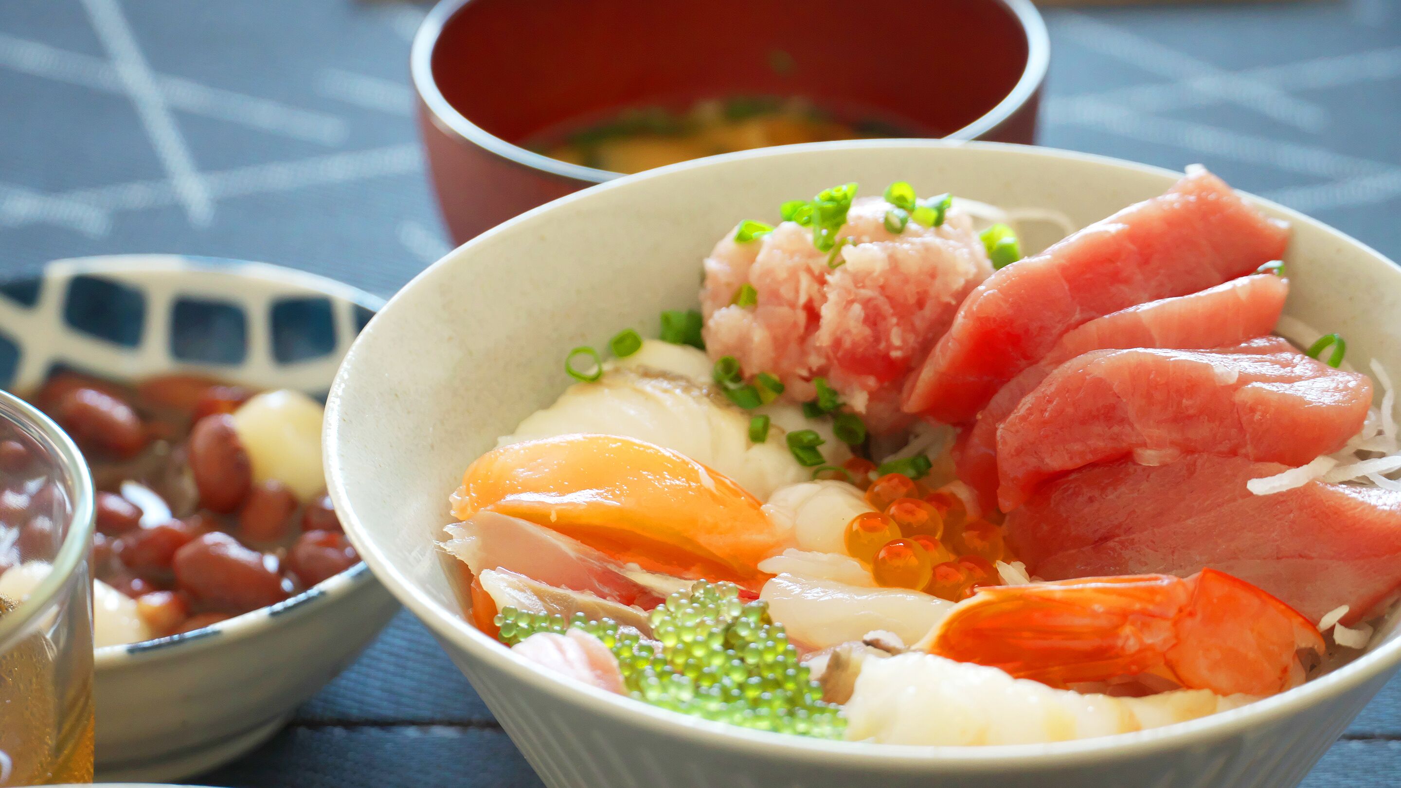 Een kom met sashimi, diverse vissoorten en garnering.