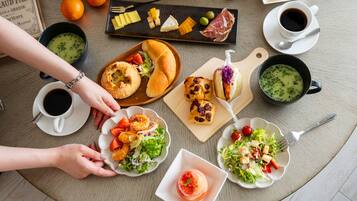A table with various dishes including shrimp, bread, and salads, along with cups of coffee and a plate of cheese.