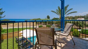Un balcon avec une piscine, des chaises et une vue sur l’océan.