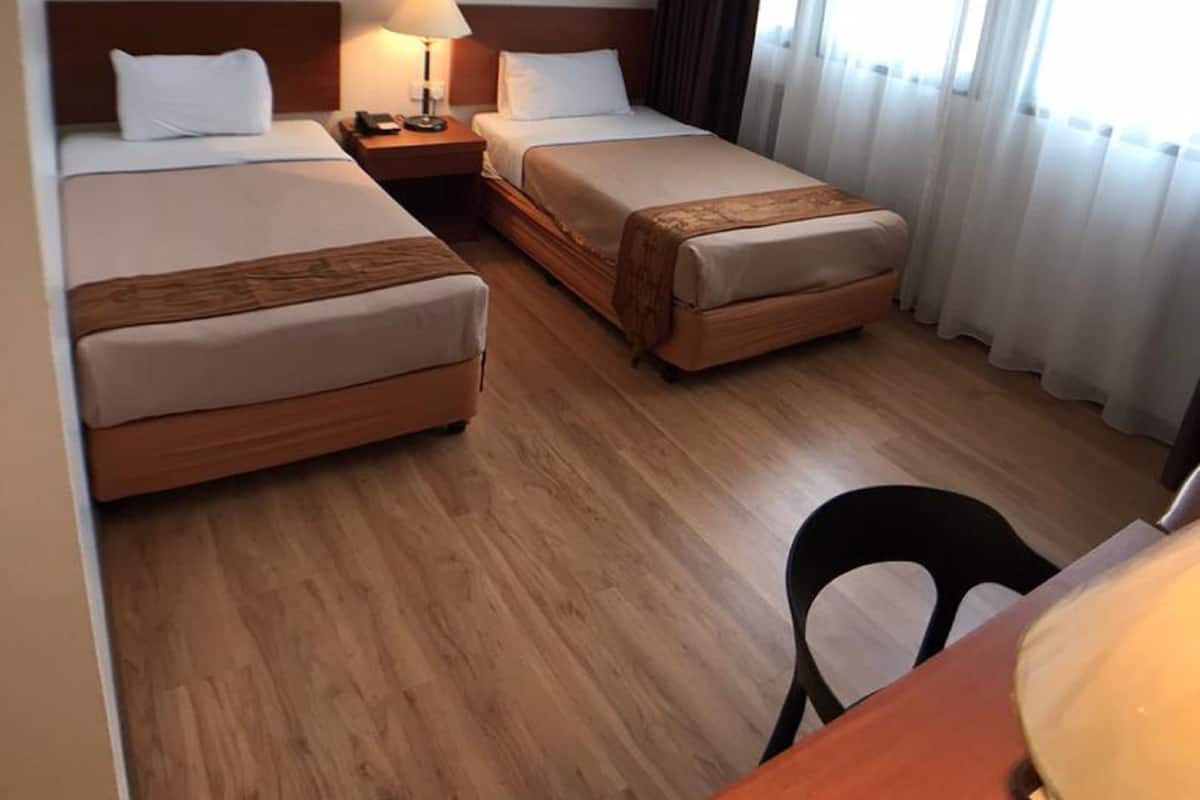 Ett hotellrum med två sängar, ett skrivbord och en stol.