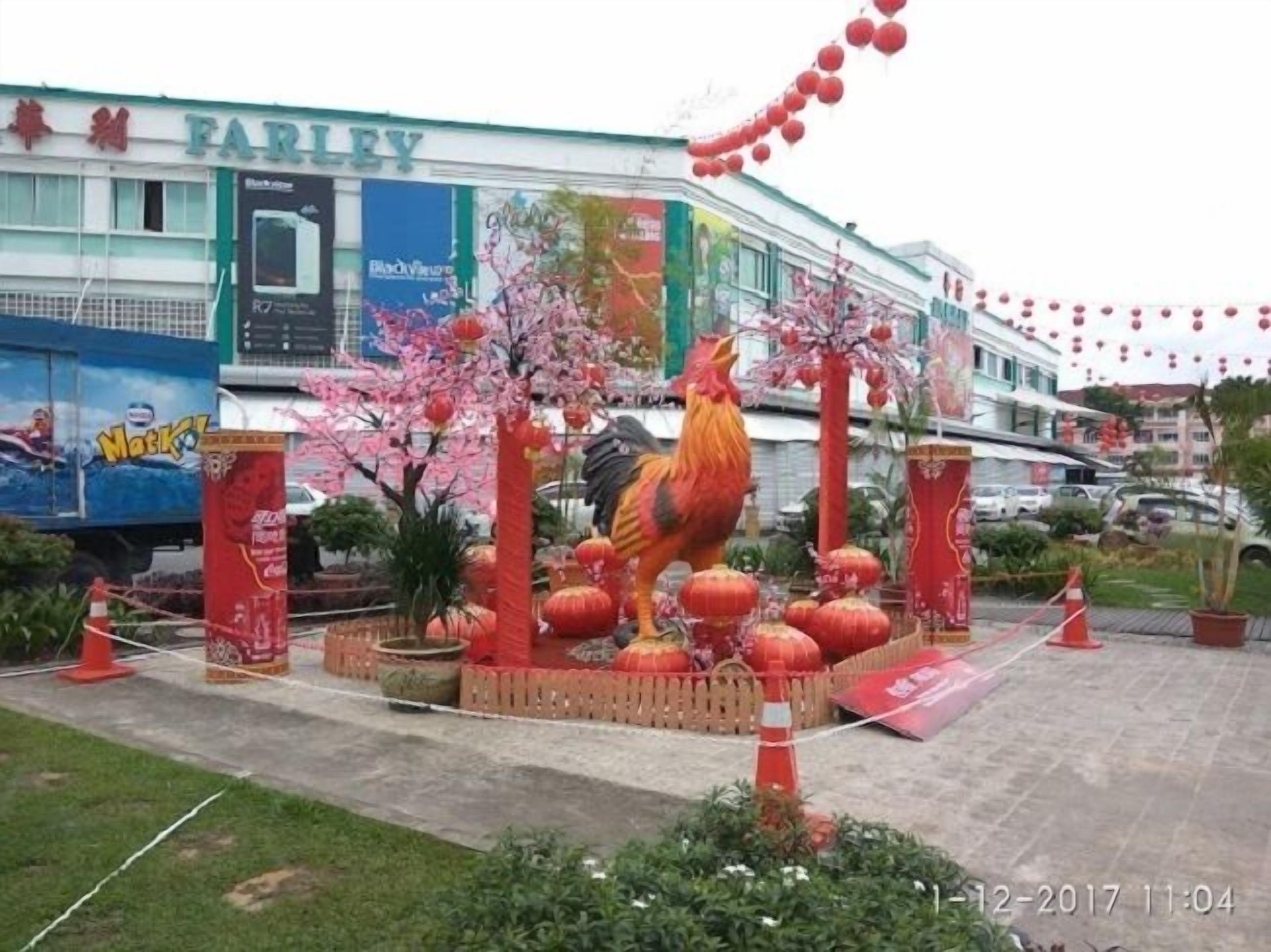 Fachada con una gran decoración de gallo, rodeada de plantas en macetas y faroles rojos.