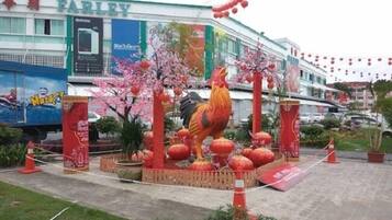 Fachada con una gran decoración de gallo, rodeada de plantas en macetas y faroles rojos.