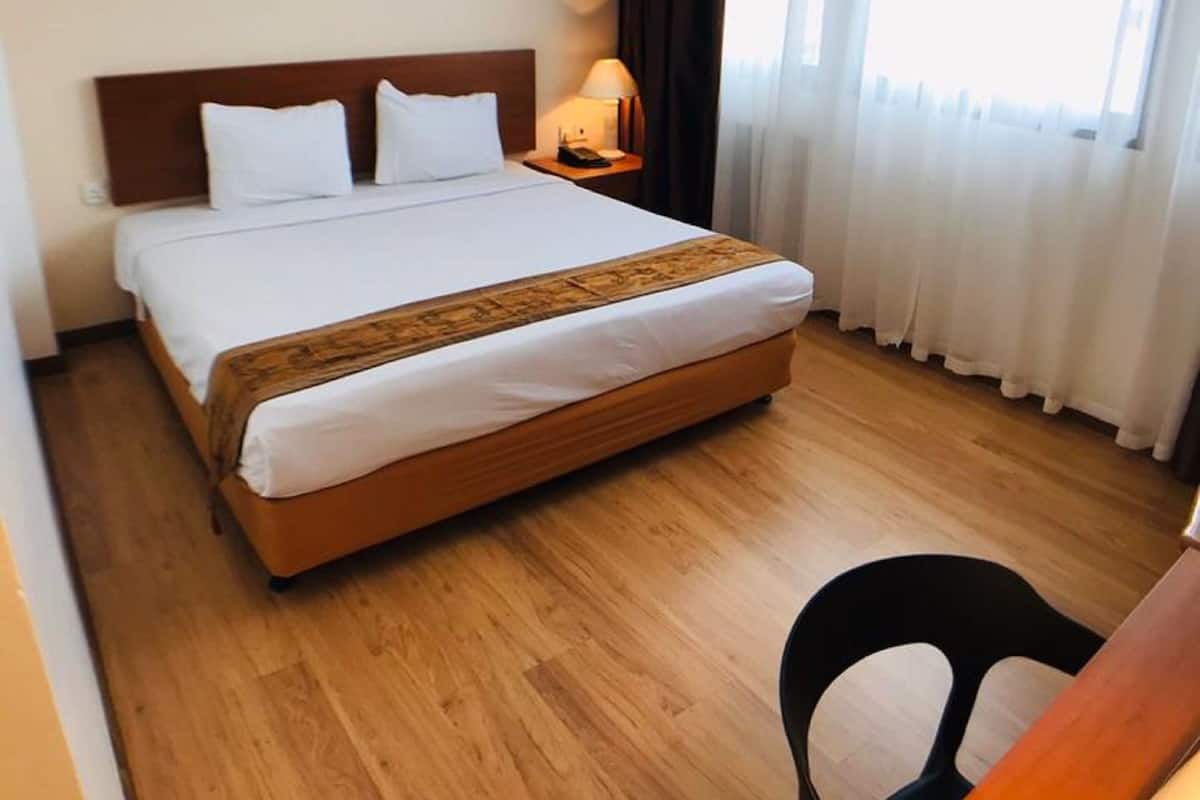 Ett hotellrum med en säng, ett skrivbord och en stol.