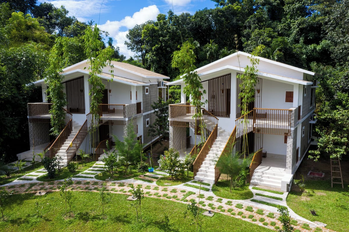 A modern residential building with two-story structures, each featuring a balcony and a staircase leading to the upper floor.