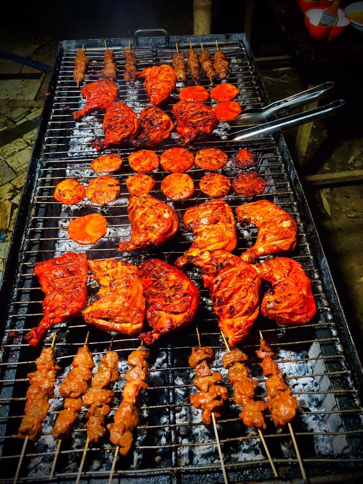 A grill with various meats and vegetables being cooked.