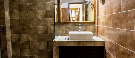 A bathroom with a stone wall, a sink, and a mirror.