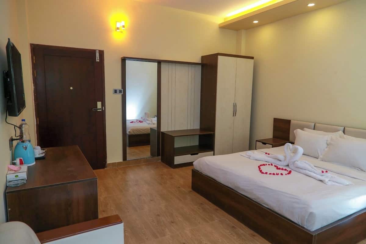 A hotel room with a bed, a wardrobe, a desk, and a television.