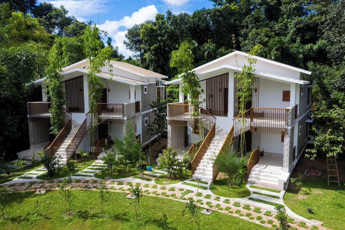 A modern residential building with two-story structures, each featuring a balcony and a staircase leading to the upper floor.