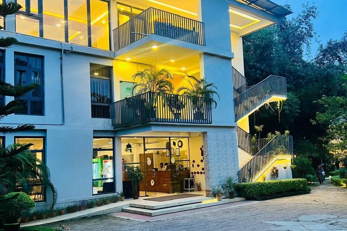A multi-story hotel with a glass facade, outdoor seating area, and a landscaped courtyard.