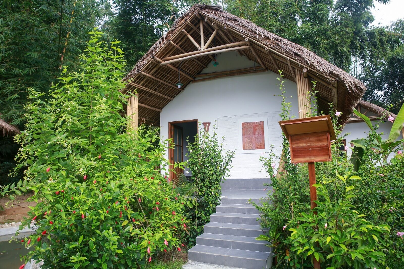A traditional bamboo-roofed house with a staircase leading to the entrance.