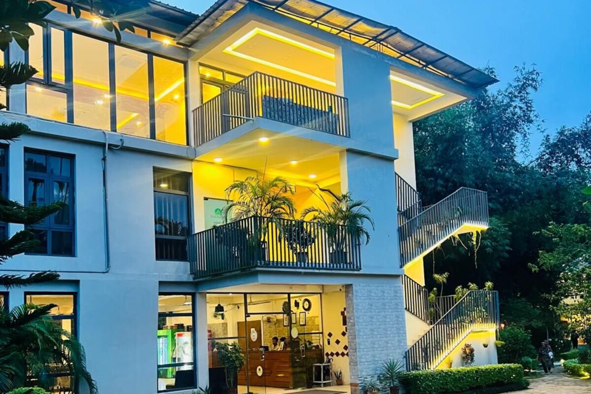 A multi-story hotel with a glass facade, outdoor seating area, and a landscaped courtyard.