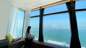 A room with a large window offering a view of the sea and cityscape. - Oasis Aurum 181 Hotel (Hong Kong)
