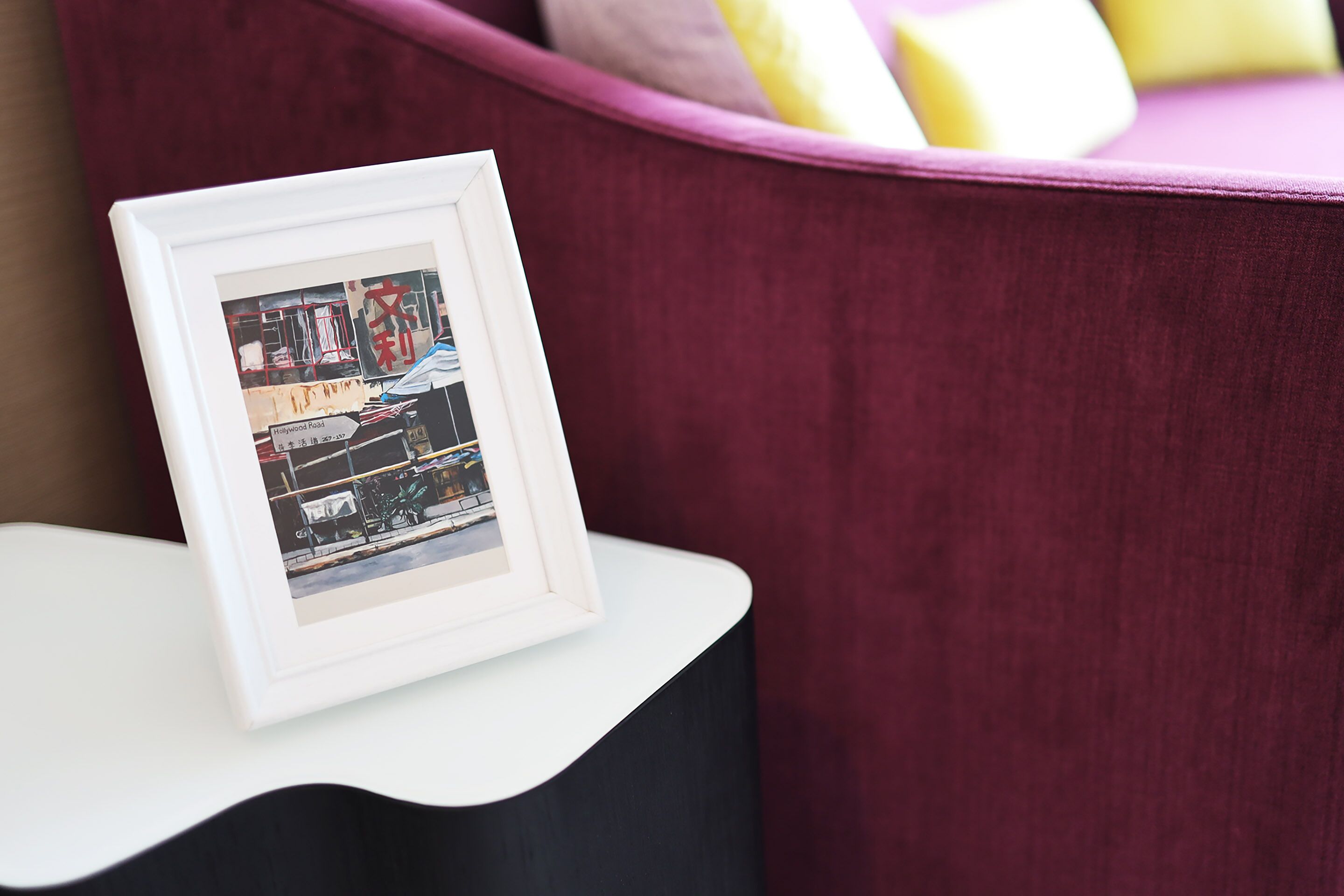A framed photograph on a white table against a maroon background.