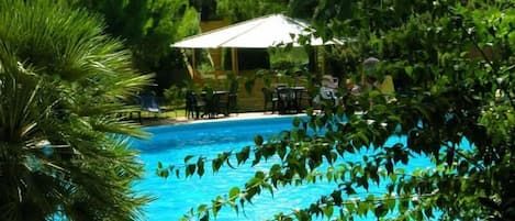 Una piscina al aire libre de temporada, sillones reclinables de piscina