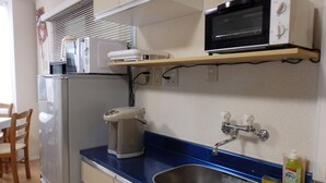 A compact kitchen with a refrigerator, a microwave, a coffee maker, and a sink.