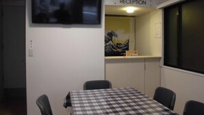 A reception area with a television, a reception desk, and a painting on the wall.