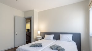 Une chambre d’hôtel avec un grand lit, deux oreillers, une table de chevet avec une lampe et une porte donnant sur une salle de bain.